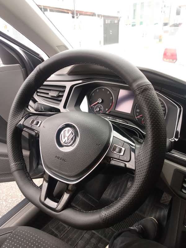 Imagem de volante de um carro da Volkswagen com capa costurada e linha preta.
