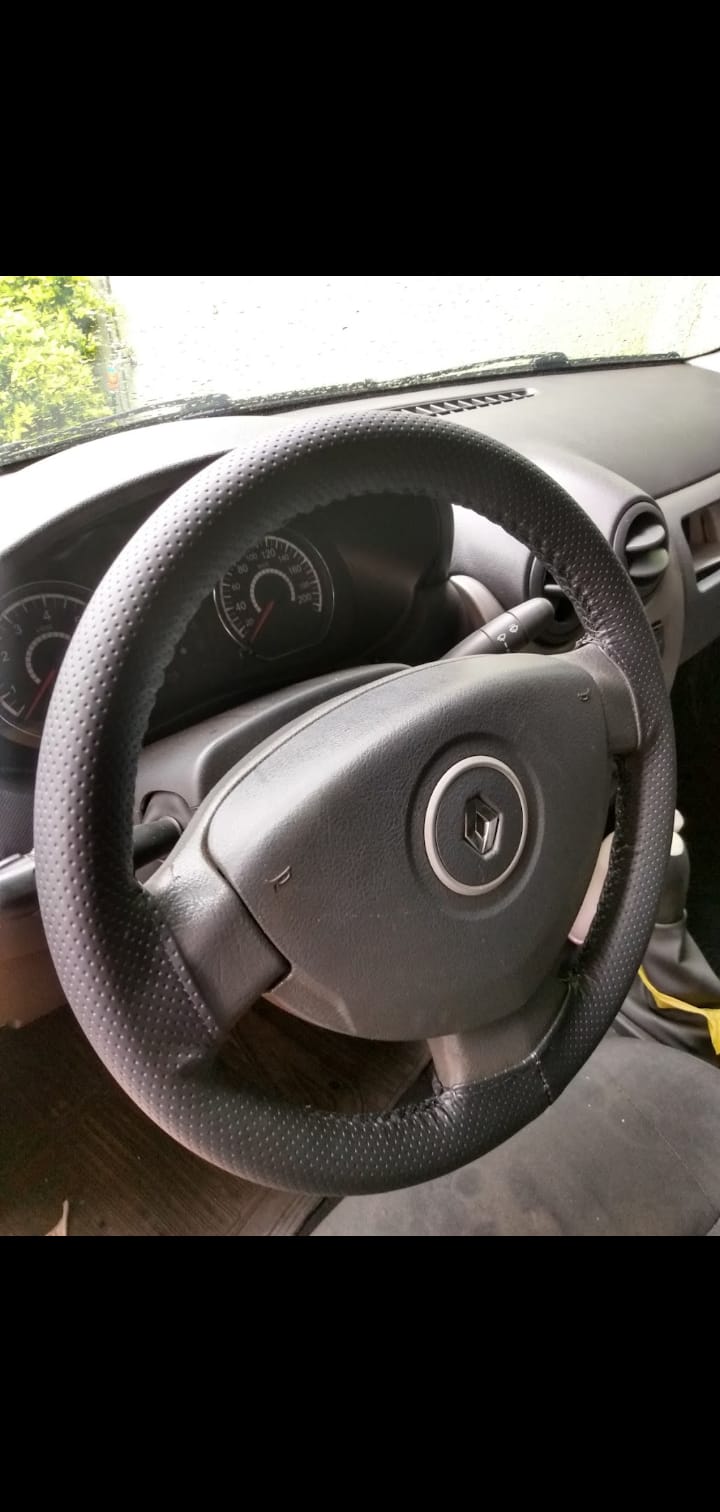Imagem de volante de um carro da Renault com capa costurada e linha preta.