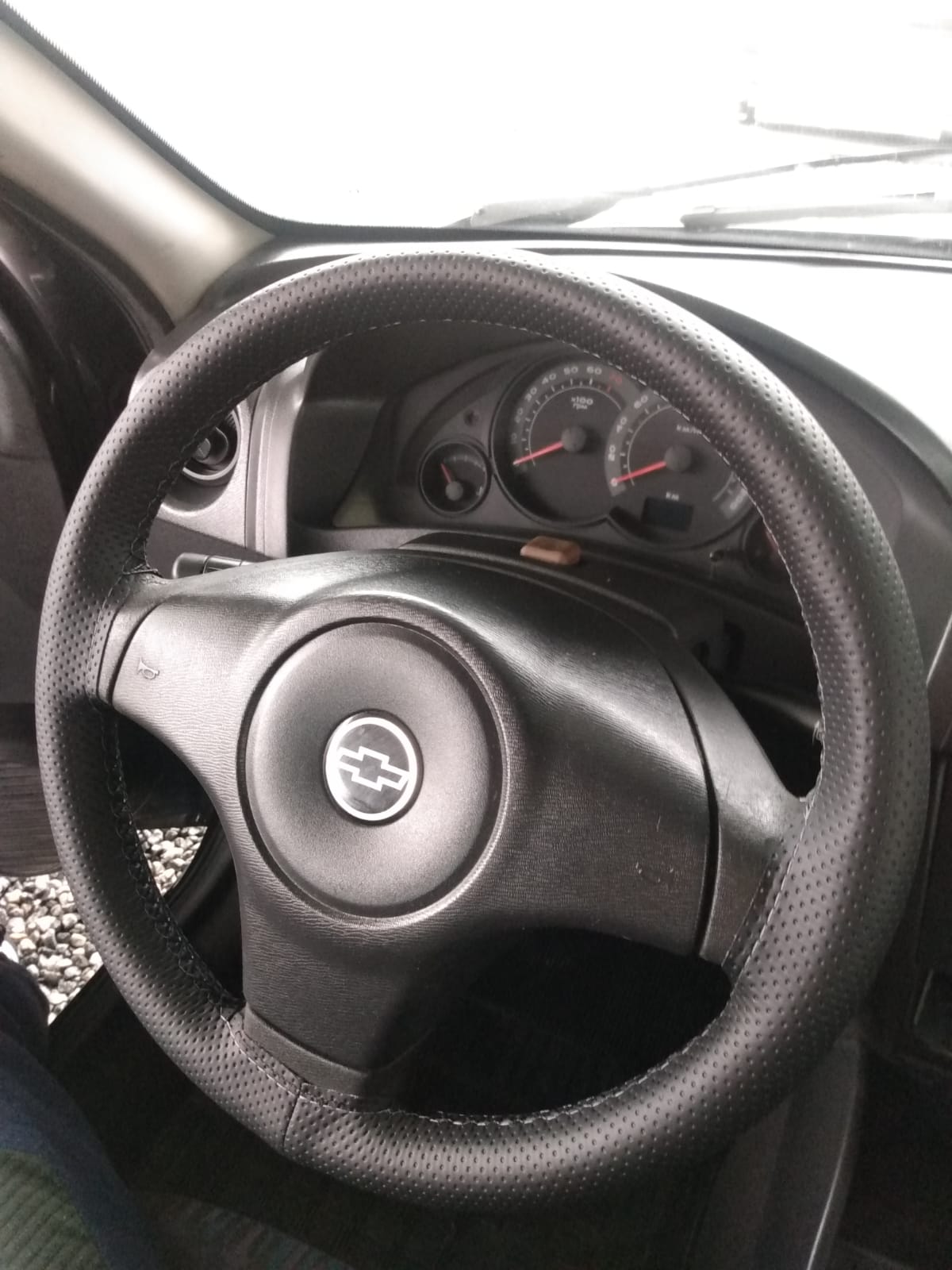 Imagem de volante de um carro da Ford com capa costurada e linha preta.